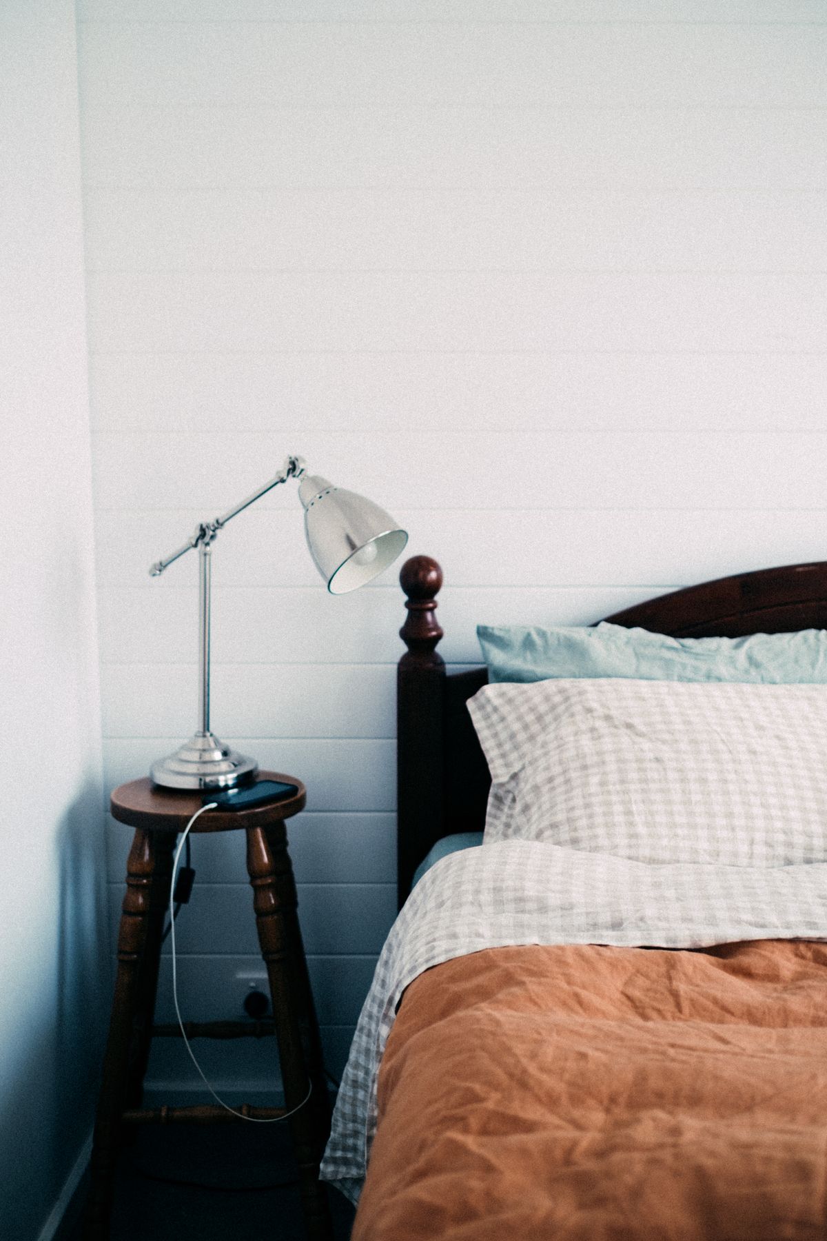 Small stool with a lamp beside a bed