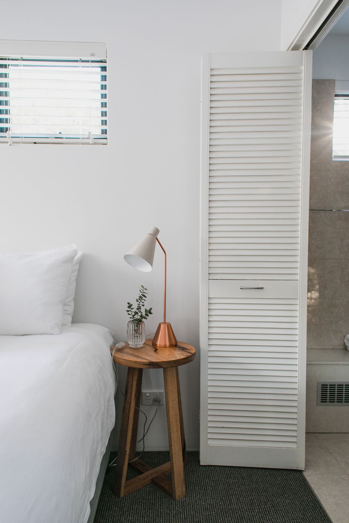 Narrow side table beside a bed